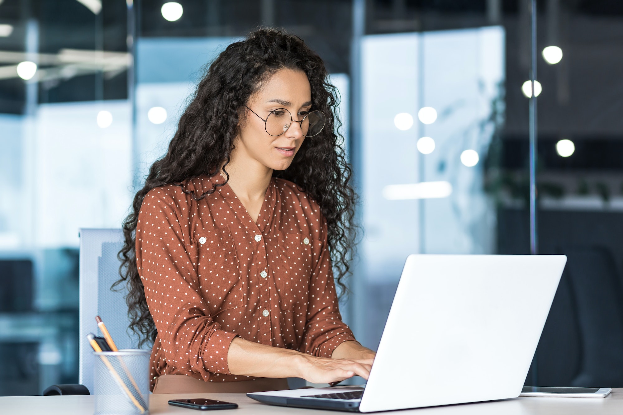 Beautiful indian woman programmer web developer focused and confident working on laptop writing code