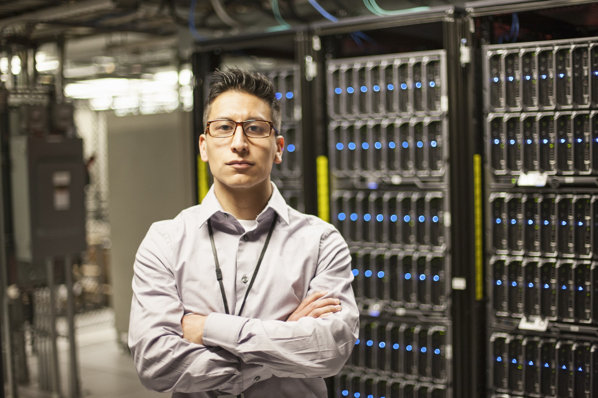 Hispanic man technician doing diagnostic tests on computer servers in a large server farm.