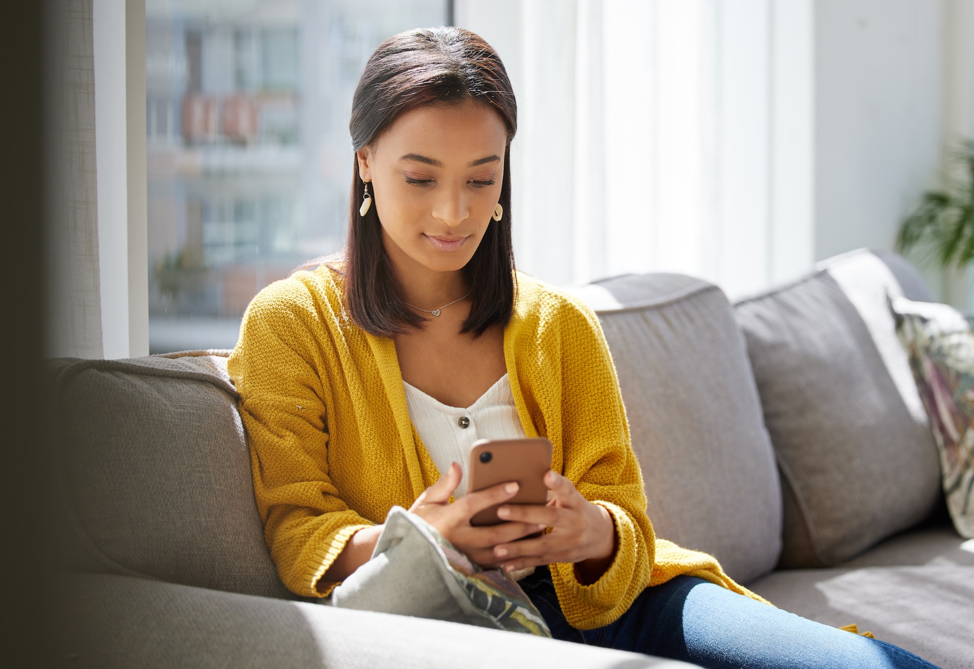 Phones have many uses. Shot of a young woman using a phone at home.