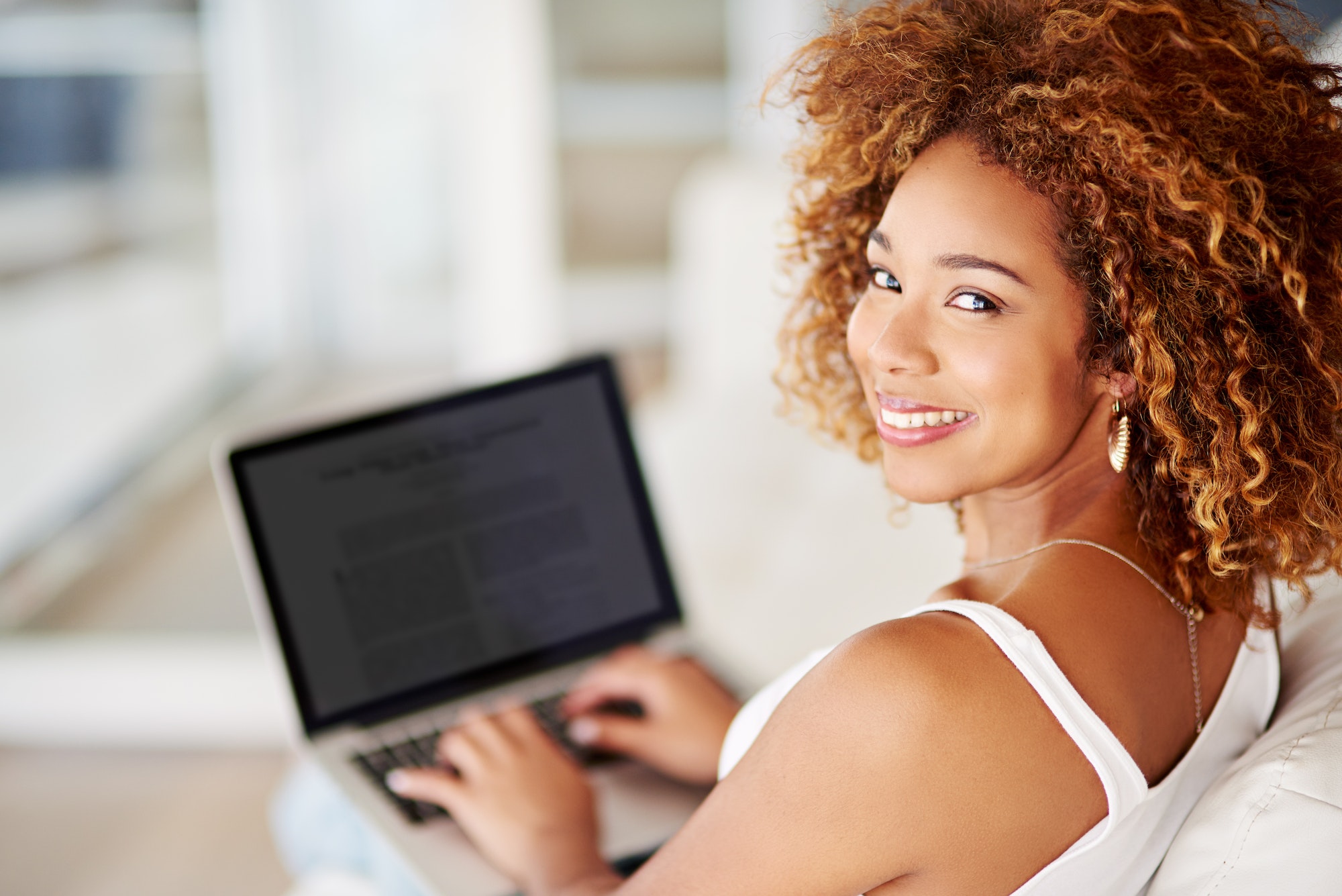 Portrait of a young woman using a laptop on the sofa at home